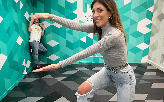 Visitors interacting with optical illusion at Museum of Illusions, Thessaloniki.