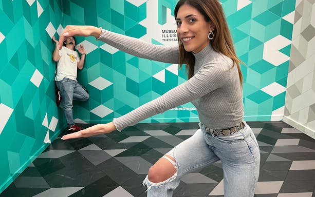 Visitors interacting with optical illusion at Museum of Illusions, Thessaloniki.