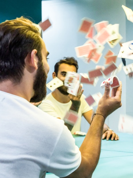 Man interacting with mirror illusion and playing cards at Museum of Illusions, Thessaloniki.