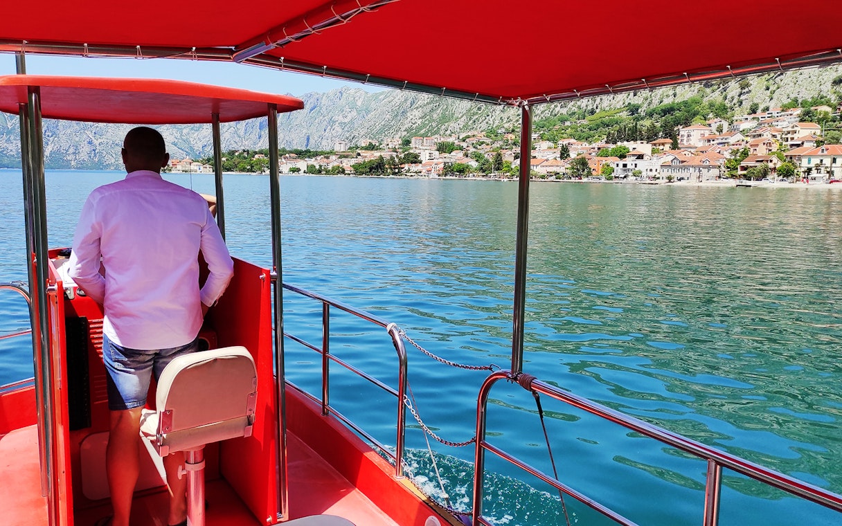 Boat on Kotor Bay with view of coastal town and mountains, Montenegro.