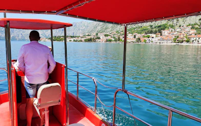 Boat on Kotor Bay with view of coastal town and mountains, Montenegro.