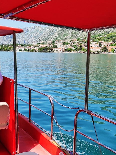 Boat on Kotor Bay with view of coastal town and mountains, Montenegro.
