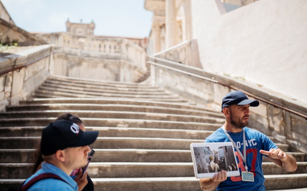 Tour guide showing Game of Thrones filming location on stone steps in Dubrovnik.