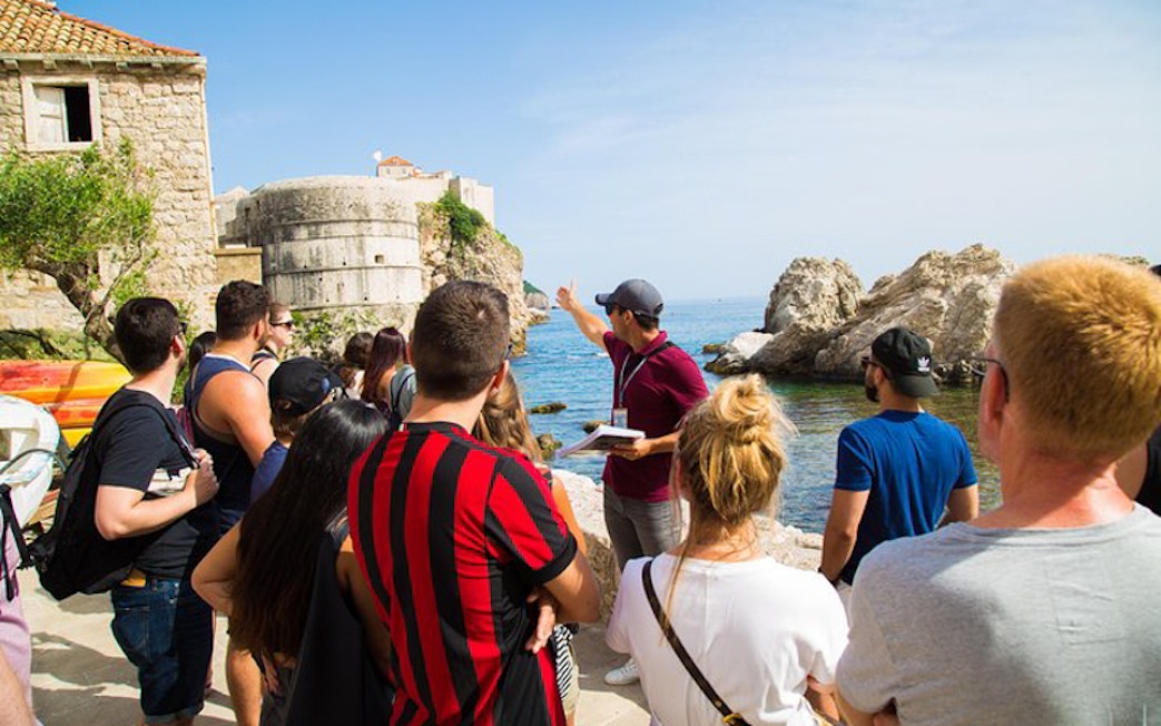 Tour group in Dubrovnik exploring Game of Thrones filming locations by the sea.