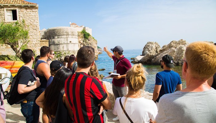 Tour group in Dubrovnik exploring Game of Thrones filming locations by the sea.