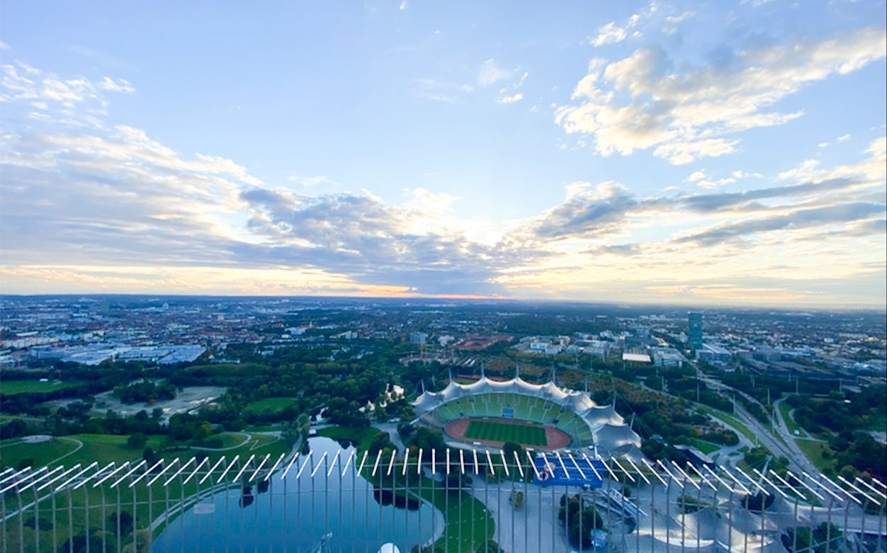 Aerial view of Munich's Olympic Stadium and park at sunset.