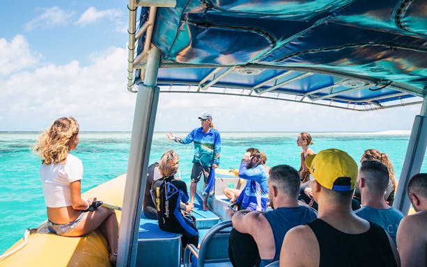 Tour group on a boat with guide during Ocean Safari Tour-9, exploring clear blue waters.