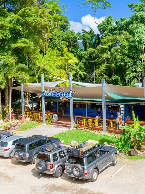 Ocean Safari Tour base with parked vehicles and lush greenery.