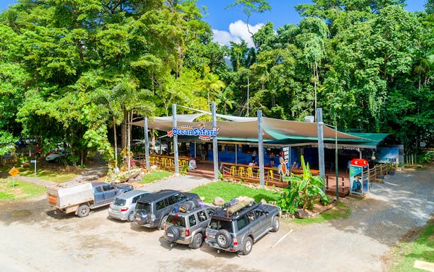 Ocean Safari Tour base with parked vehicles and lush greenery.
