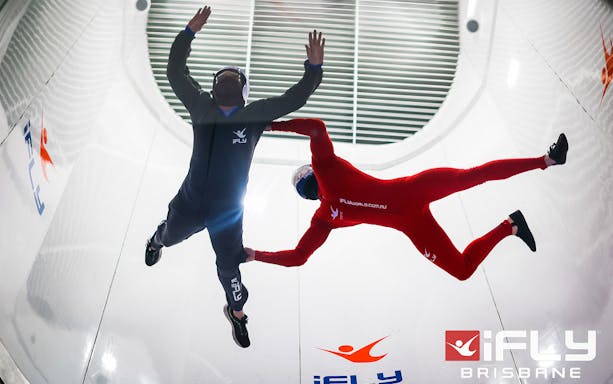 Indoor skydiving at iFly Brisbane with two participants in flight suits.
