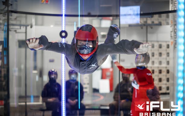 Indoor skydiving at iFly Brisbane with participant in flight suit and helmet.