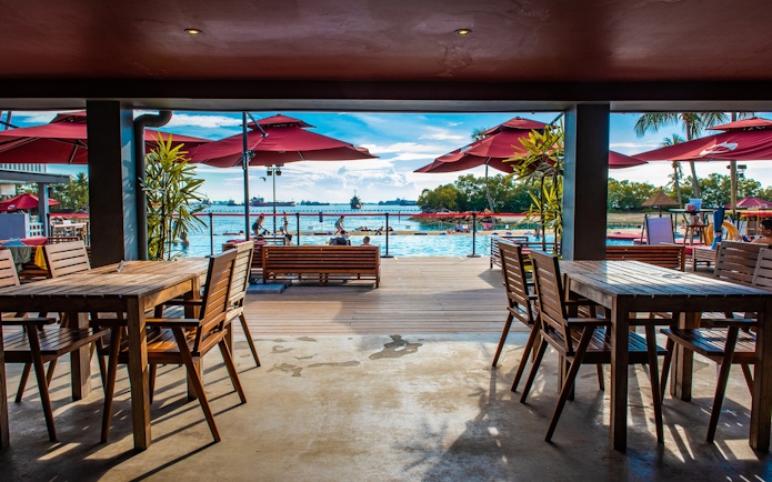 Outdoor dining area overlooking pool and ocean at Sentosa, Singapore.
