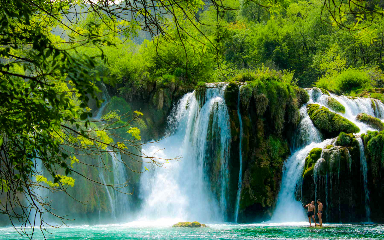 Visitors enjoying Krka Waterfalls in lush greenery, part of a tour from Split.