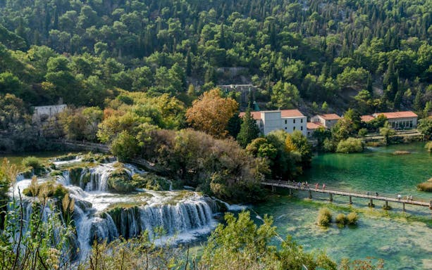 Krka Waterfalls with footbridge and surrounding greenery on tour from Split.