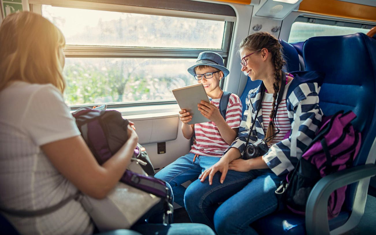 Family enjoying train ride to Meteora, Greece, with scenic views through window.