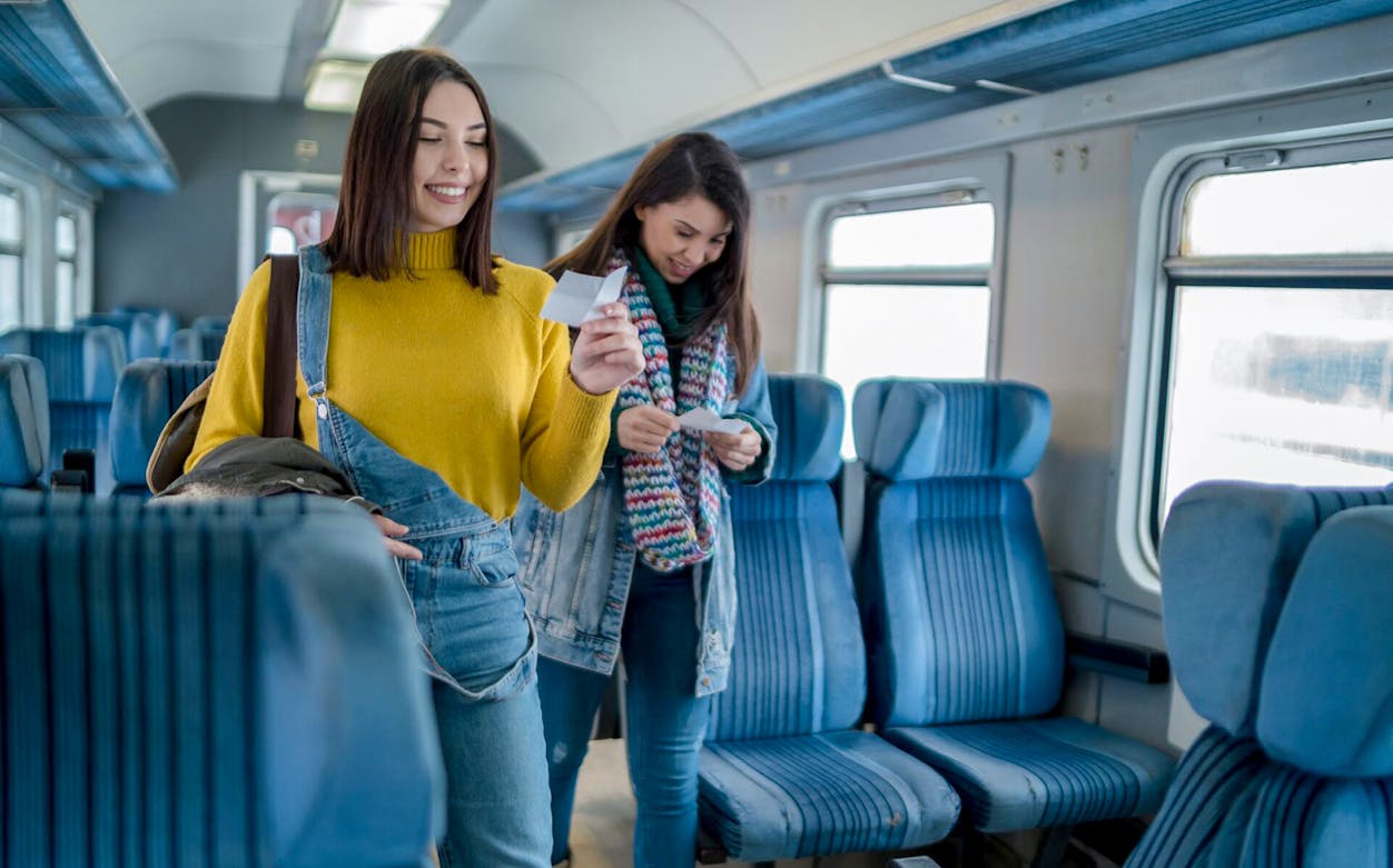 Two travelers holding tickets inside a train on the Meteora Highlights tour.