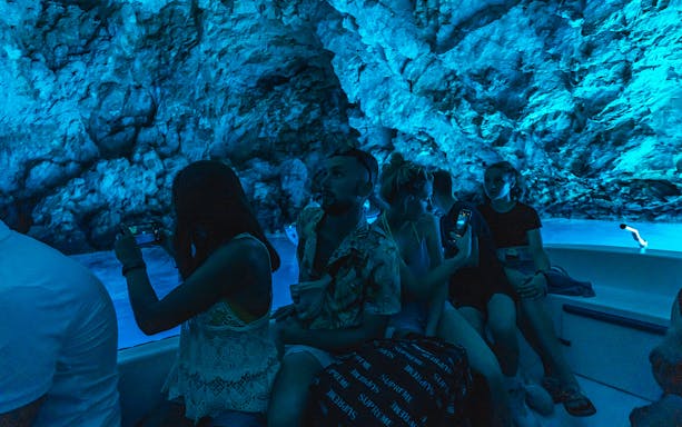 Tourists on a boat inside the illuminated Blue Cave, Hvar during a small-group tour from Split.