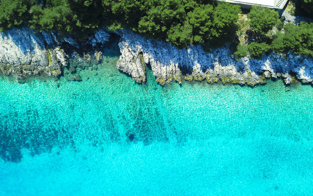 Aerial view of Blue Lagoon's turquoise waters and rocky coastline.