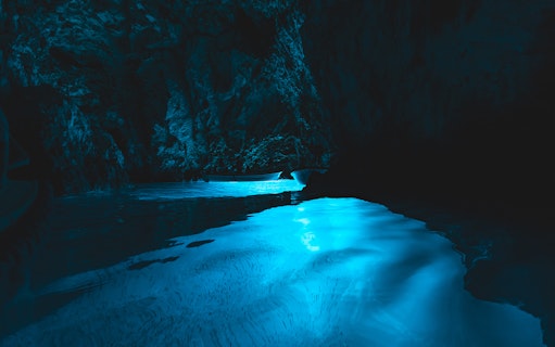 Blue Lagoon cave with illuminated blue water during half-day tour.