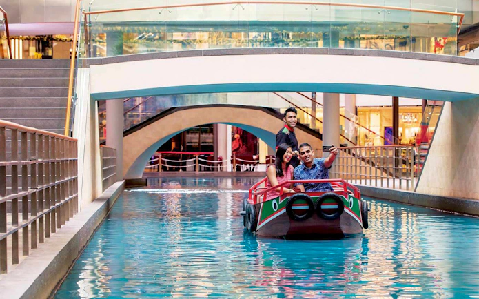 Sampan ride under a bridge at Marina Bay Sands, Singapore, with smiling passengers taking a selfie.