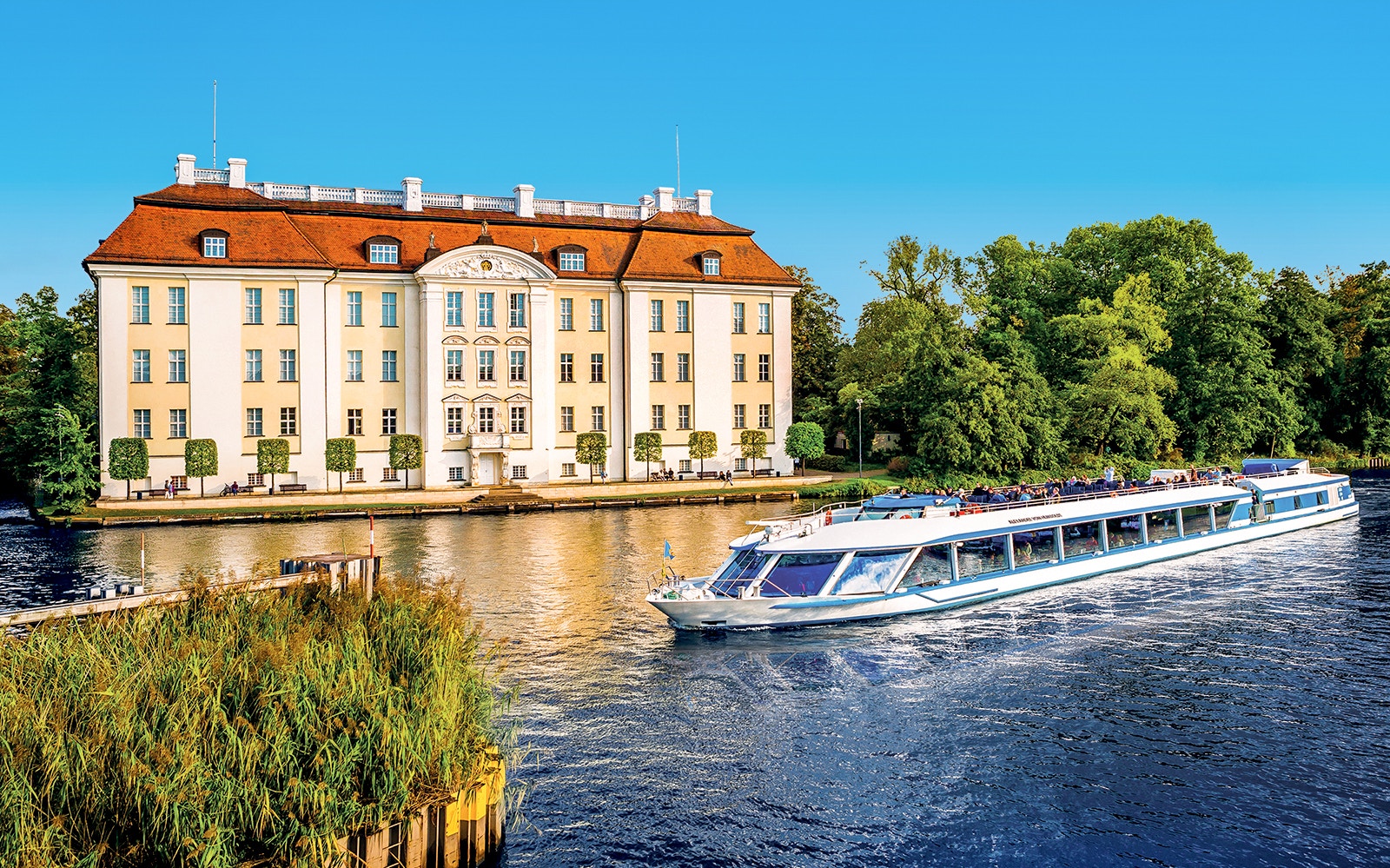 Cruise boat on Müggelsee lake near historic building, Berlin-Treptow.