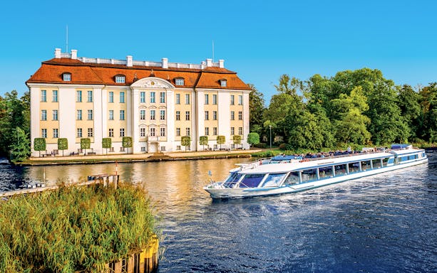 Cruise boat on Müggelsee lake near historic building, Berlin-Treptow.