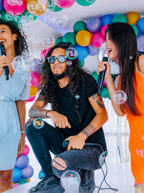 People enjoying karaoke surrounded by colorful balloons and bubbles at Ain Dubai.