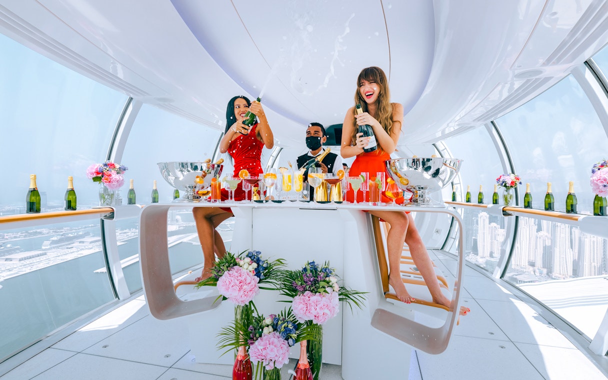 Celebration inside Ain Dubai cabin with views of Dubai skyline.
