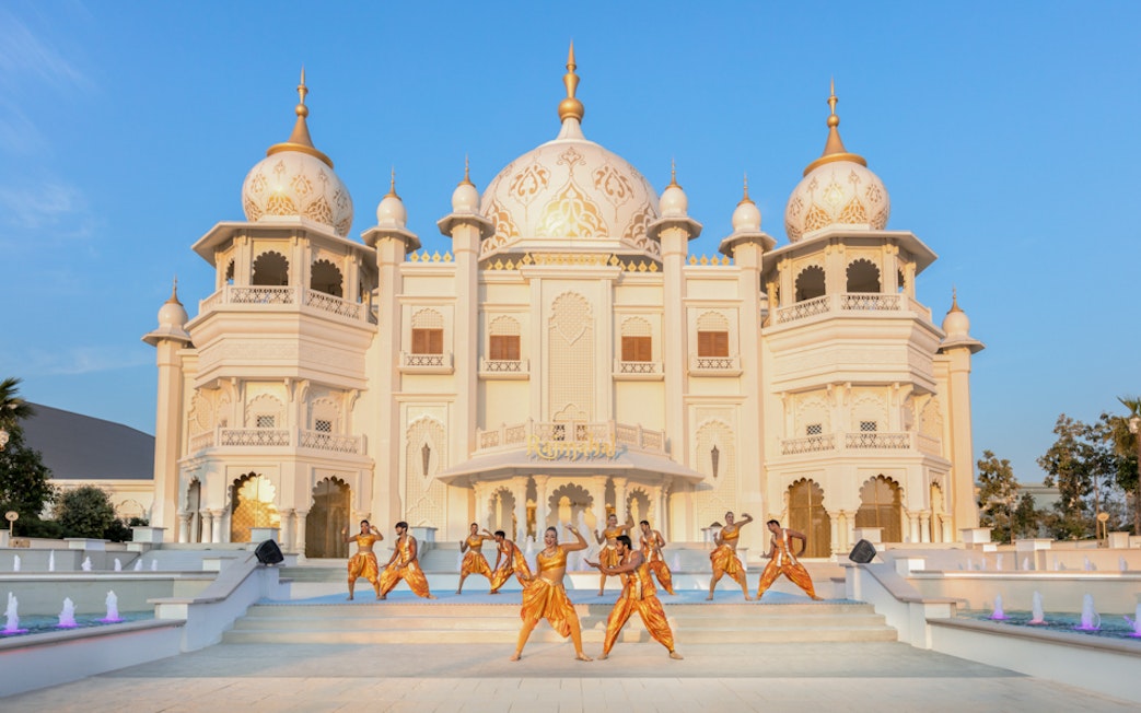 Dancers performing in front of a grand palace at BOLLYWOOD PARKS™ Dubai.