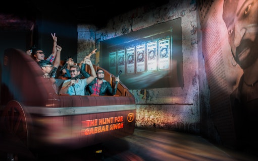Visitors on a ride at Bollywood Parks Dubai, experiencing "The Hunt for Gabbar Singh" attraction.