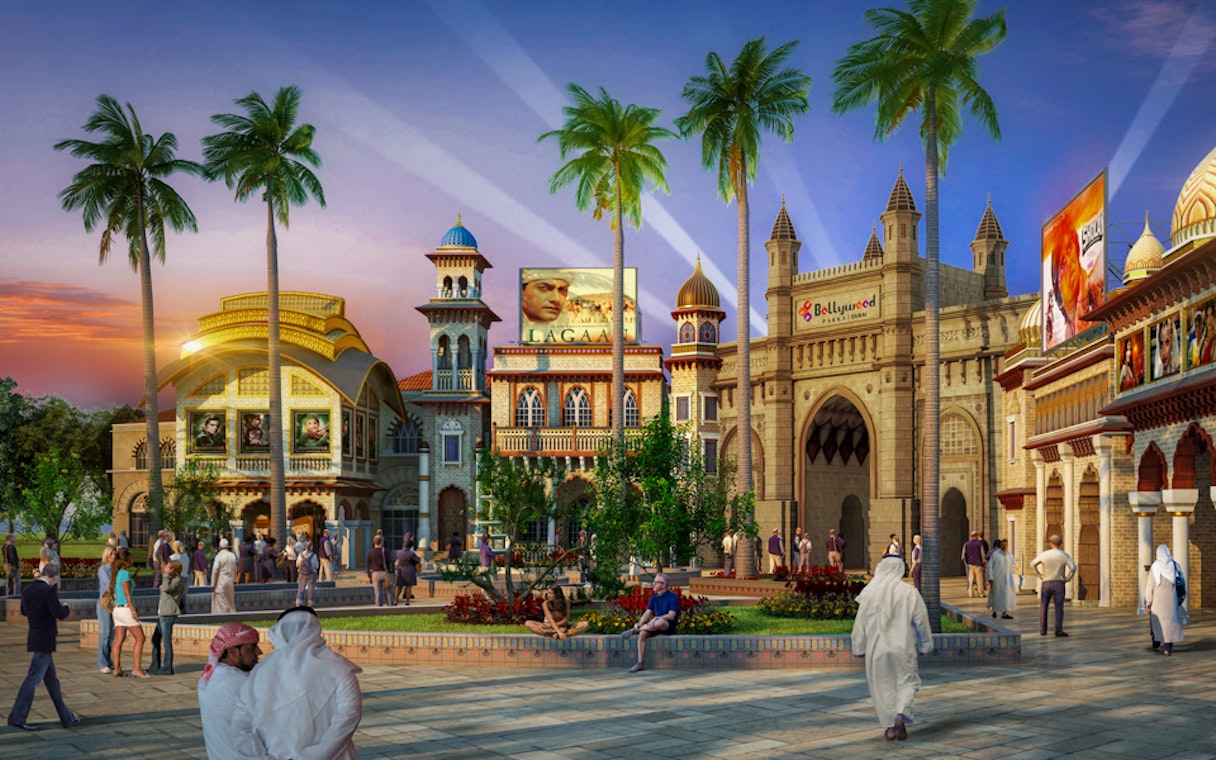 Bollywood Parks Dubai entrance with visitors and palm trees at sunset.