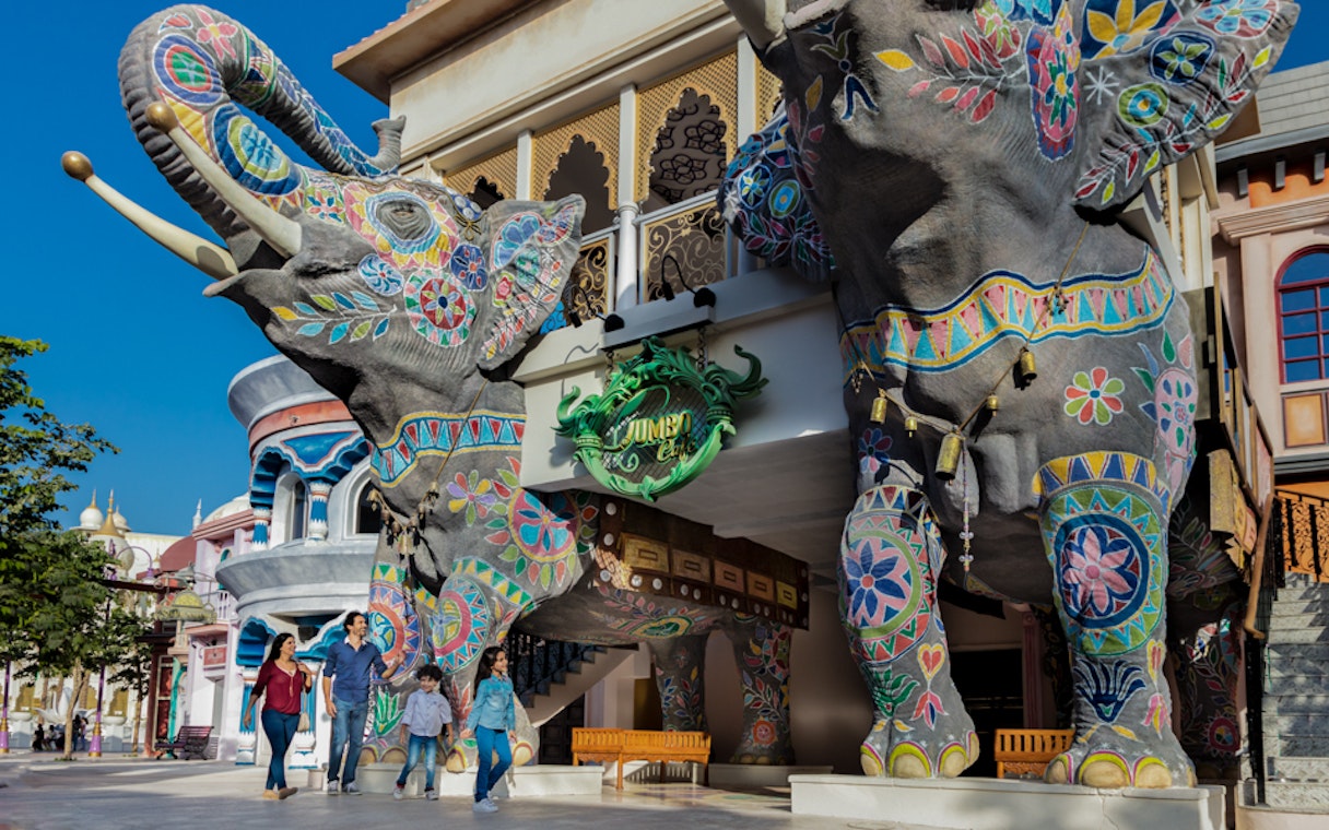 Colorful elephant statues at Bollywood Parks™ Dubai entrance with visitors walking nearby.