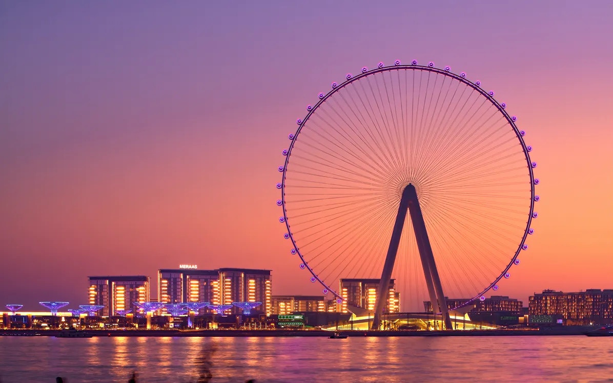 Ain Dubai Ferris wheel at sunset with city skyline in the background.