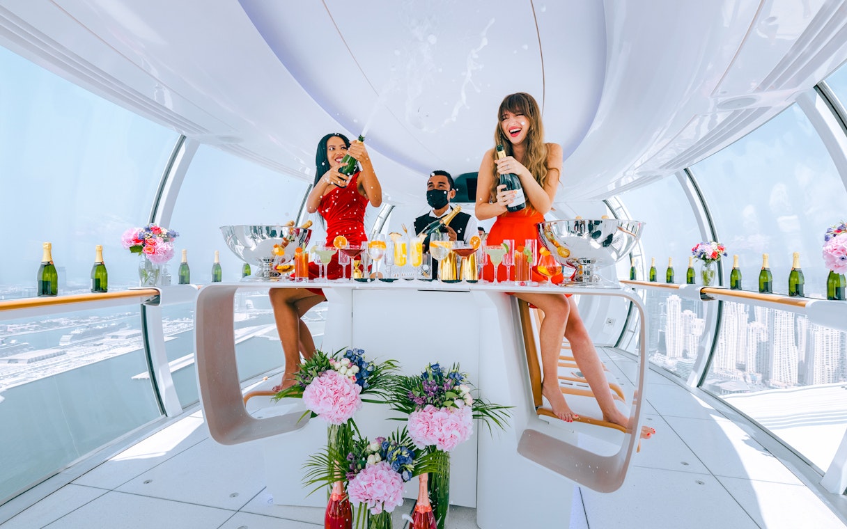Celebration inside Ain Dubai cabin with champagne and city views.