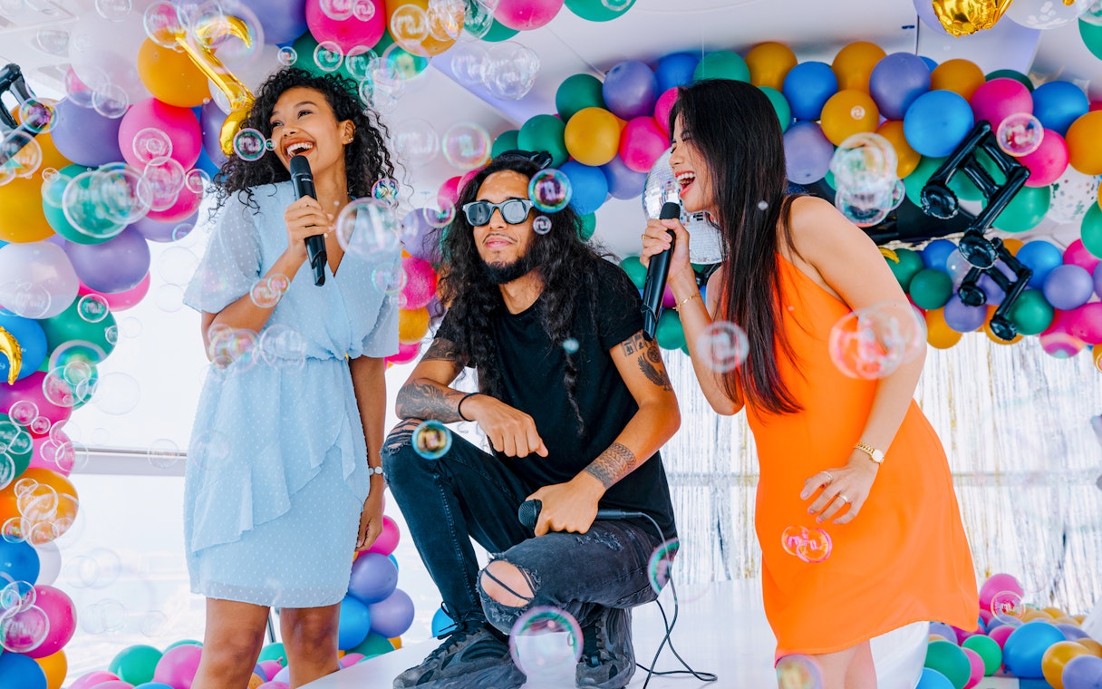 Group enjoying karaoke with colorful balloons and bubbles at Ain Dubai.