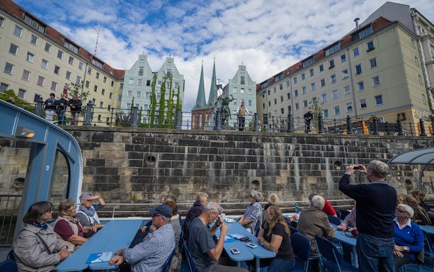 Boat tour passengers view Berlin's historic architecture and statues along the canal.