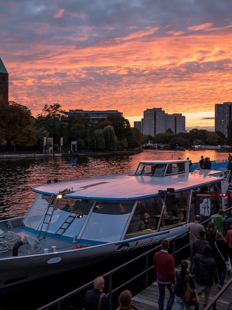 Berlin city boat tour at sunset with passengers boarding near West Harbor.