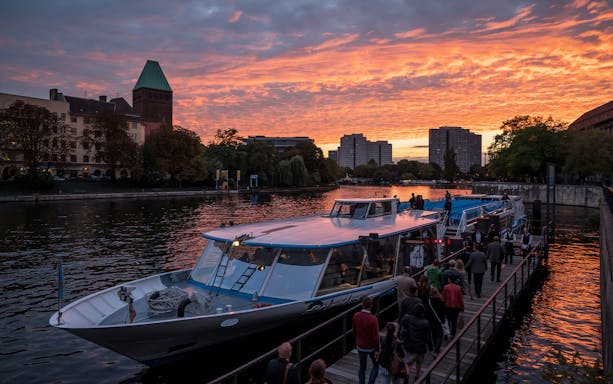 Berlin city boat tour at sunset with passengers boarding near West Harbor.
