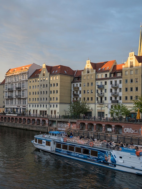 Boat cruising through Berlin city center with Berlin Cathedral and TV Tower in the background.
