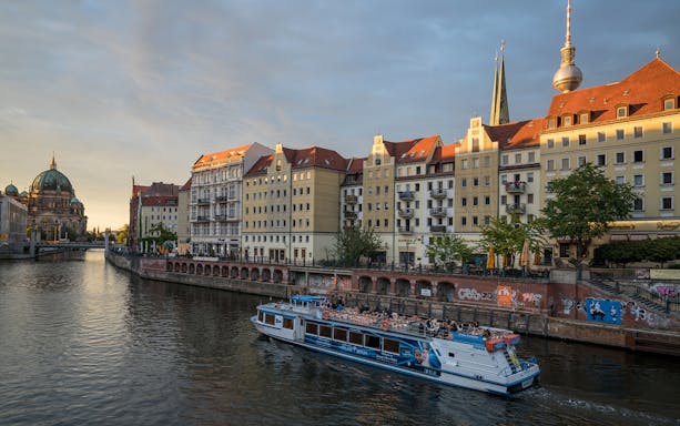 Boat cruising through Berlin city center with Berlin Cathedral and TV Tower in the background.
