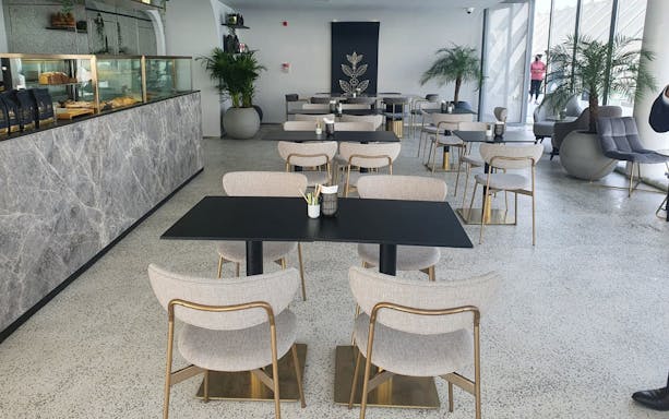Dining area at The View at the Palm, featuring modern tables and chairs with a pastry counter.