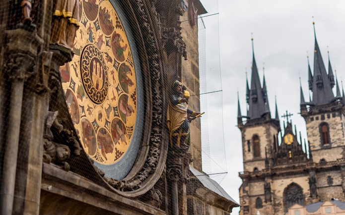 Astronomical Clock detail with Prague Castle spires in the background.