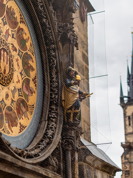 Astronomical Clock detail with Prague Castle spires in the background.