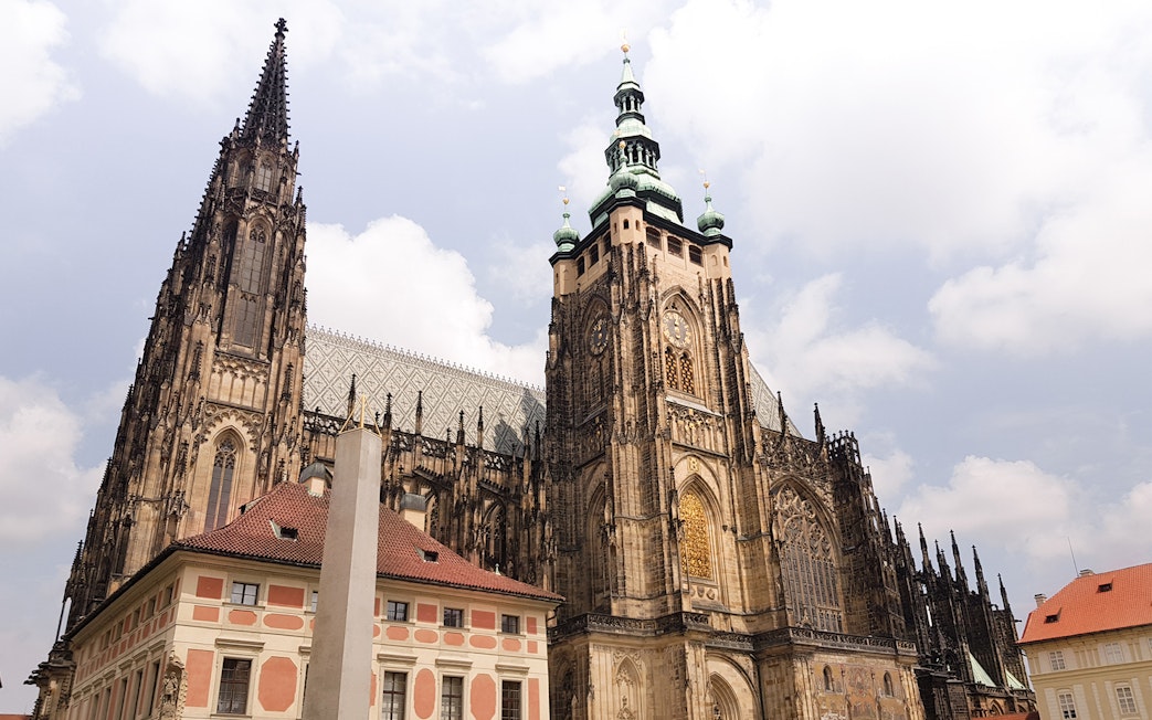 Prague Castle exterior with gothic architecture under a cloudy sky.