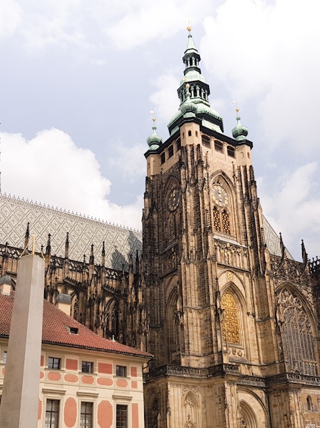 Prague Castle exterior with gothic architecture under a cloudy sky.
