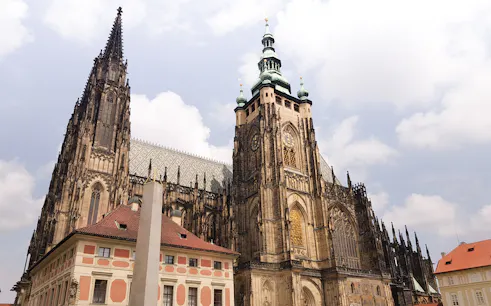 Prague Castle exterior with gothic architecture under a cloudy sky.