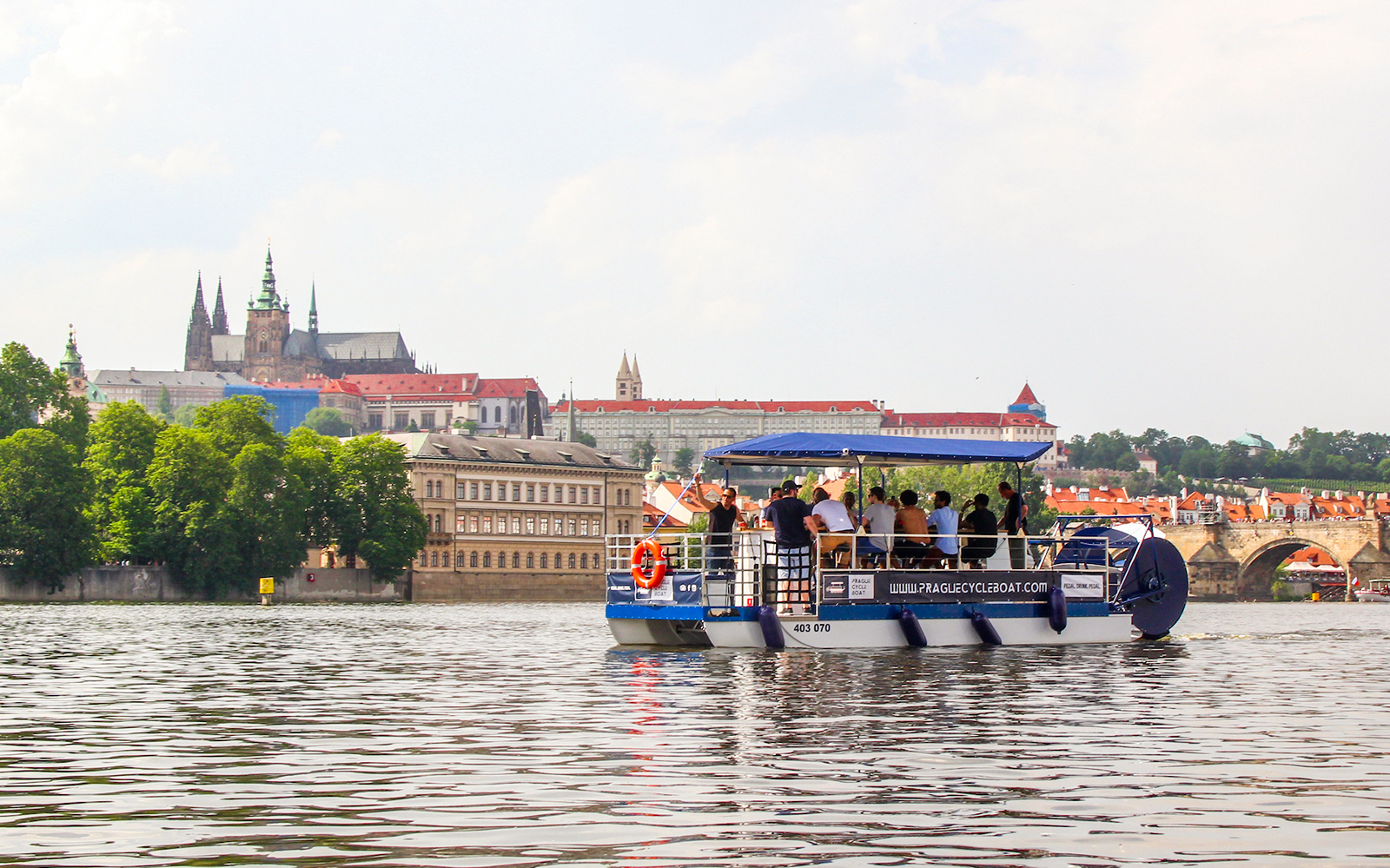 Prague Cycle Boat on Vltava River with Prague Castle in the background.