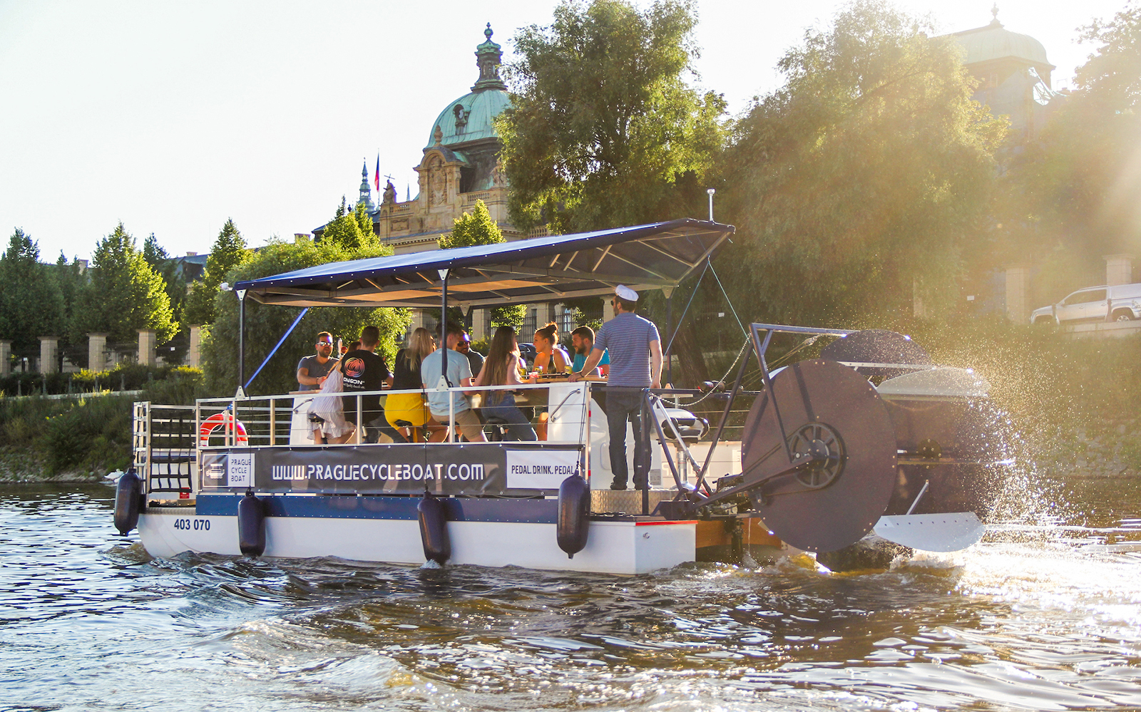 Prague cycle boat with tourists near the royal palace on a sunny day.