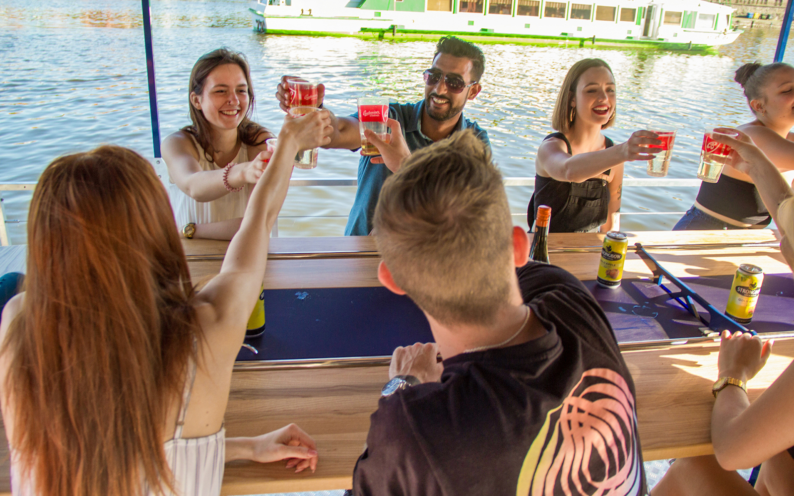 Tourists enjoying drinks on a Prague cycle boat tour.
