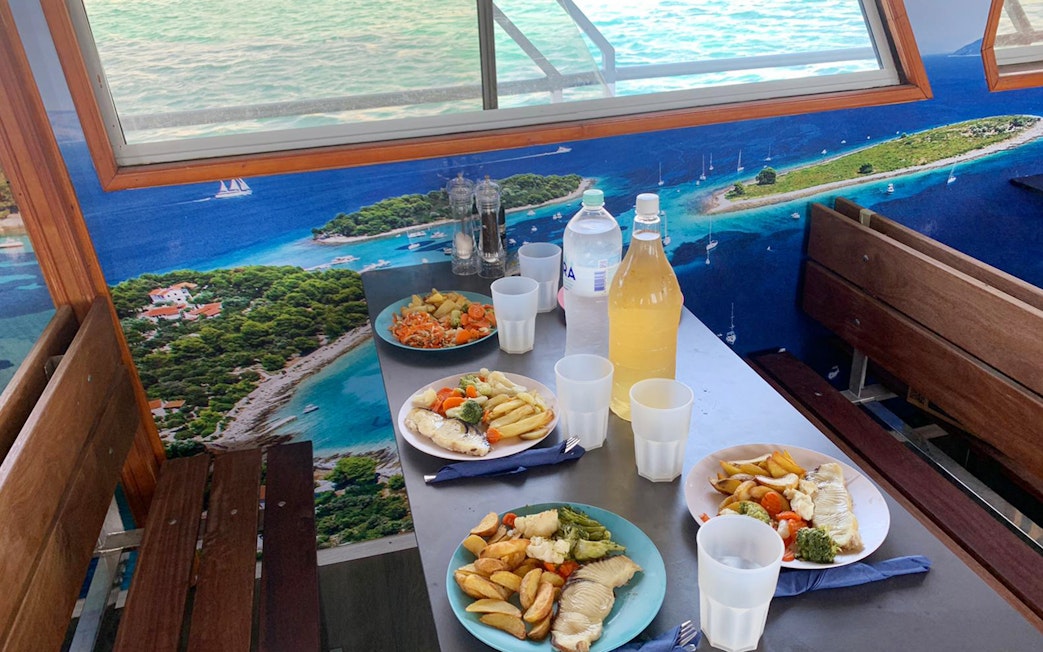 Lunch setup on a cruise with plates of fish and vegetables, Split Blue Lagoon tour.